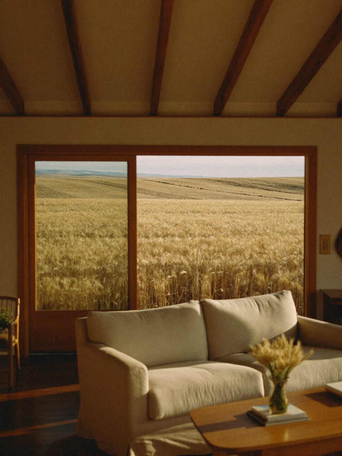 A farmhouse living room with windows looking over a golden wheat field