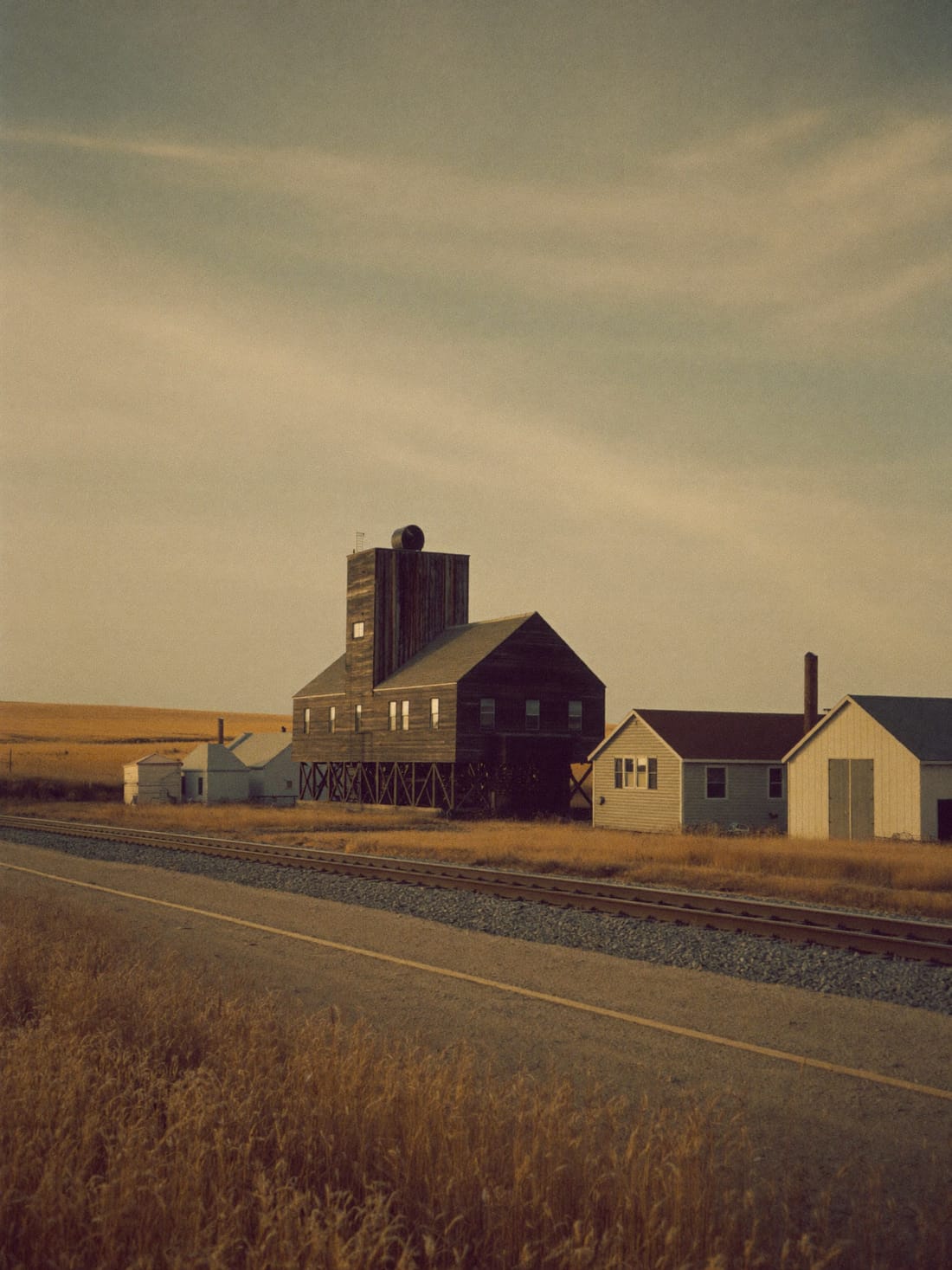 A prairie grain elevator at the edge of a small Northern Alberta town at golden hour