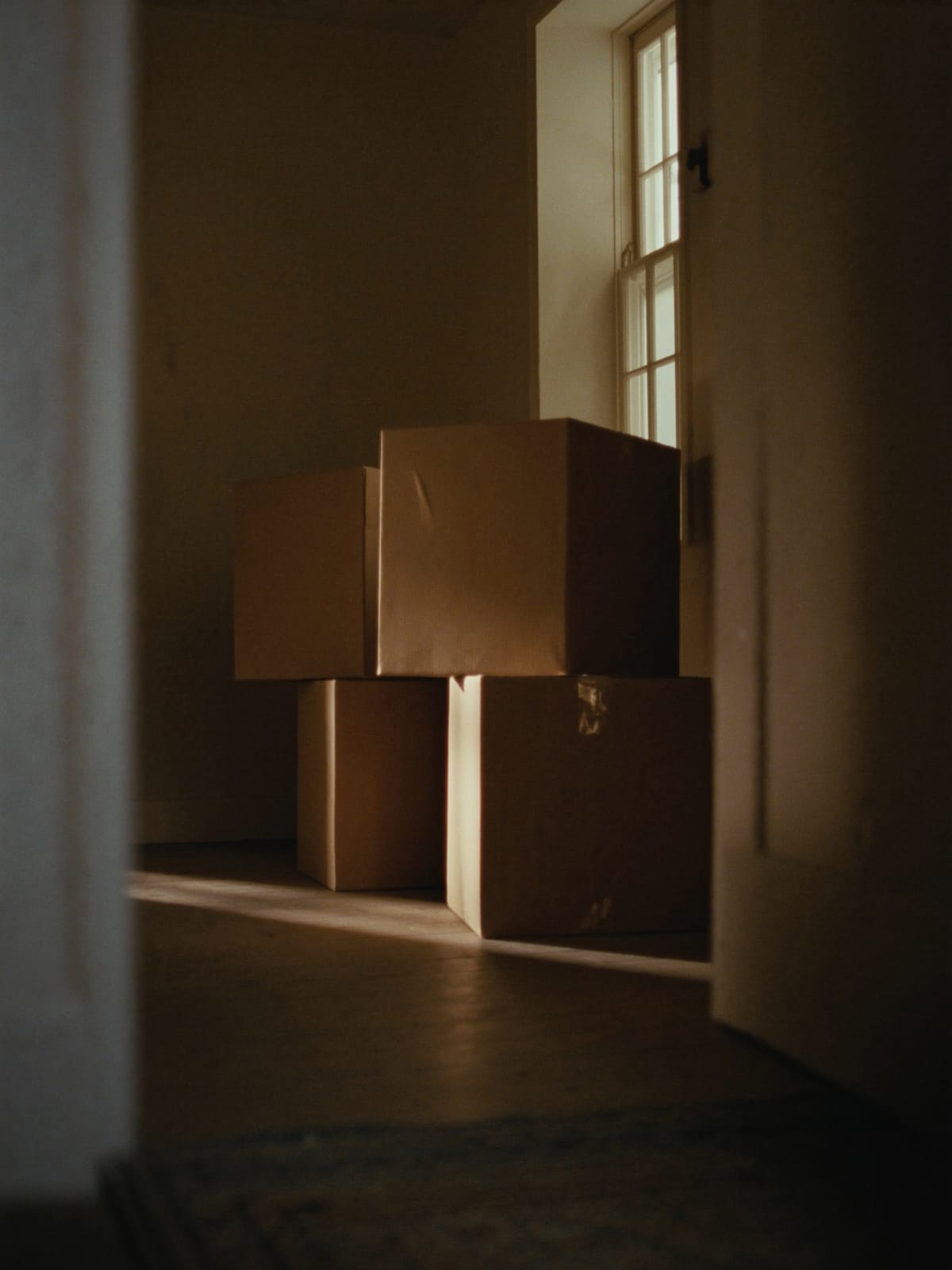 Plain moving boxes stacked in a sunlit farmhouse entryway